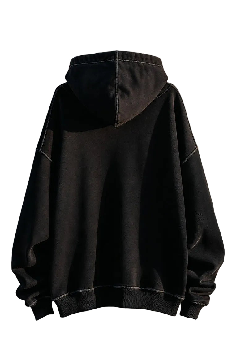 Black hoodie on a person against a textured wall.