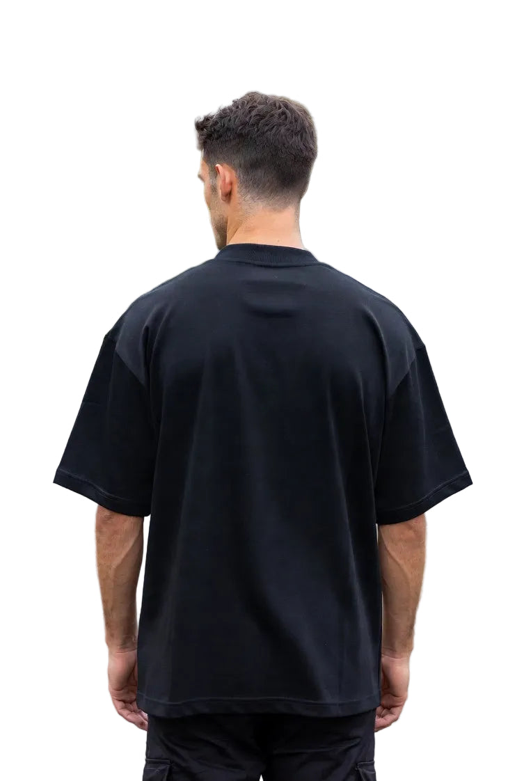 Person wearing a black t-shirt walking on a road with trees and houses in the background