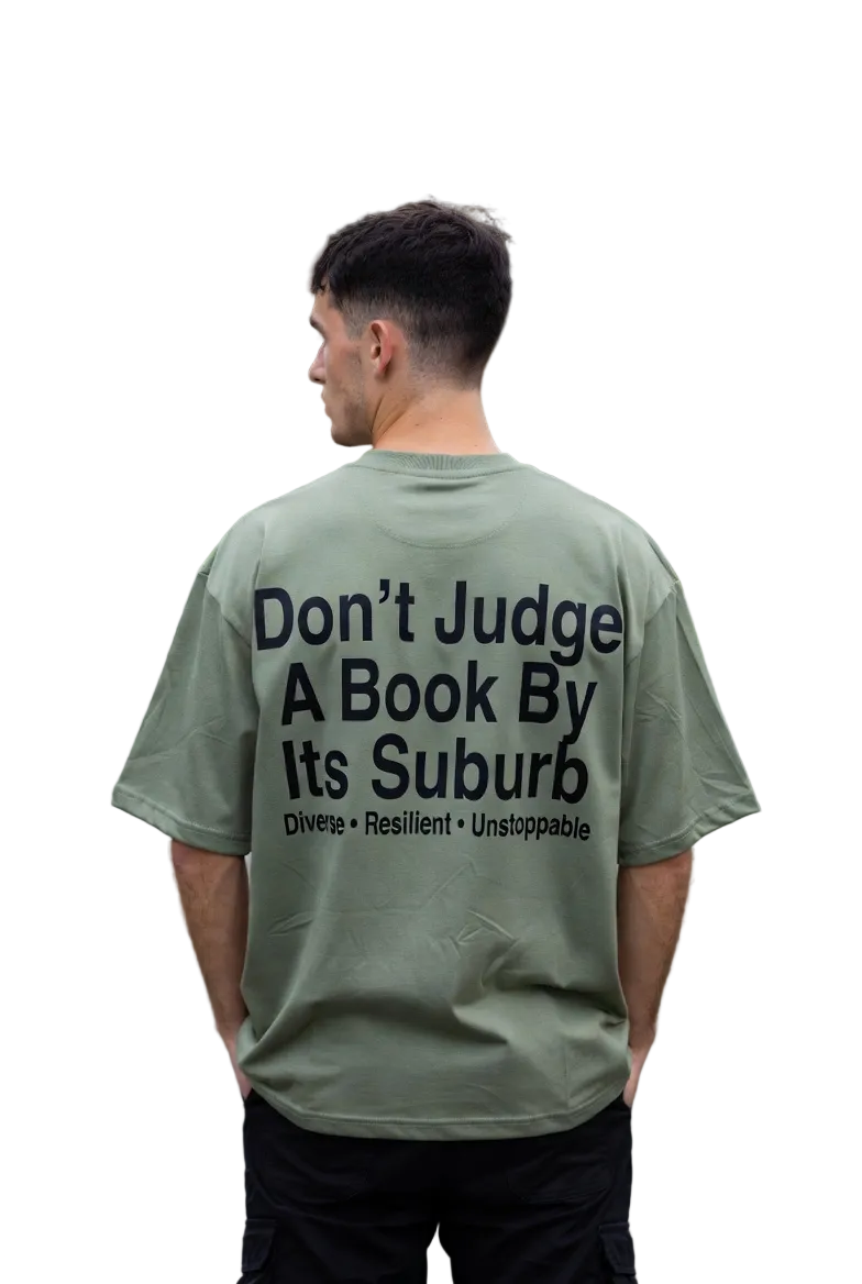 Man wearing a green t-shirt with a motivational message on the back, standing on a residential street.